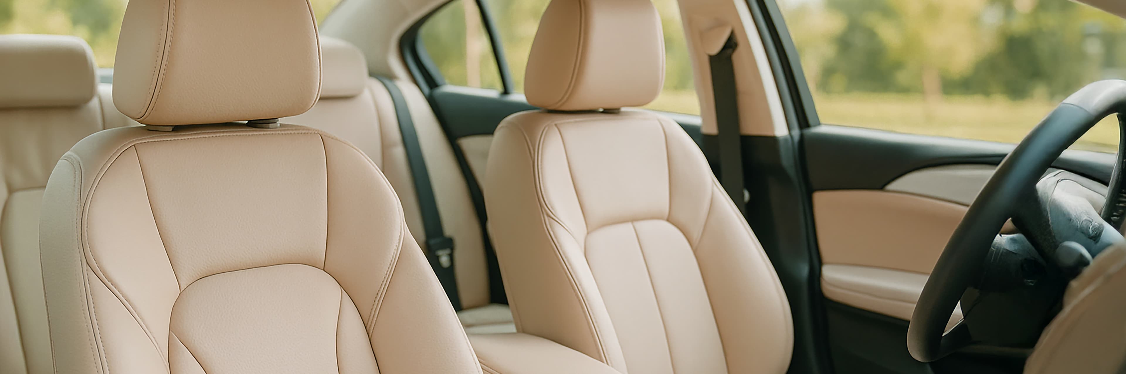 Vue de l'intérieur d'une voiture avec des sièges en cuir beige, un volant sur la droite, la lumière du soleil passant par les fenêtres et un paysage vert flou à l'extérieur.
