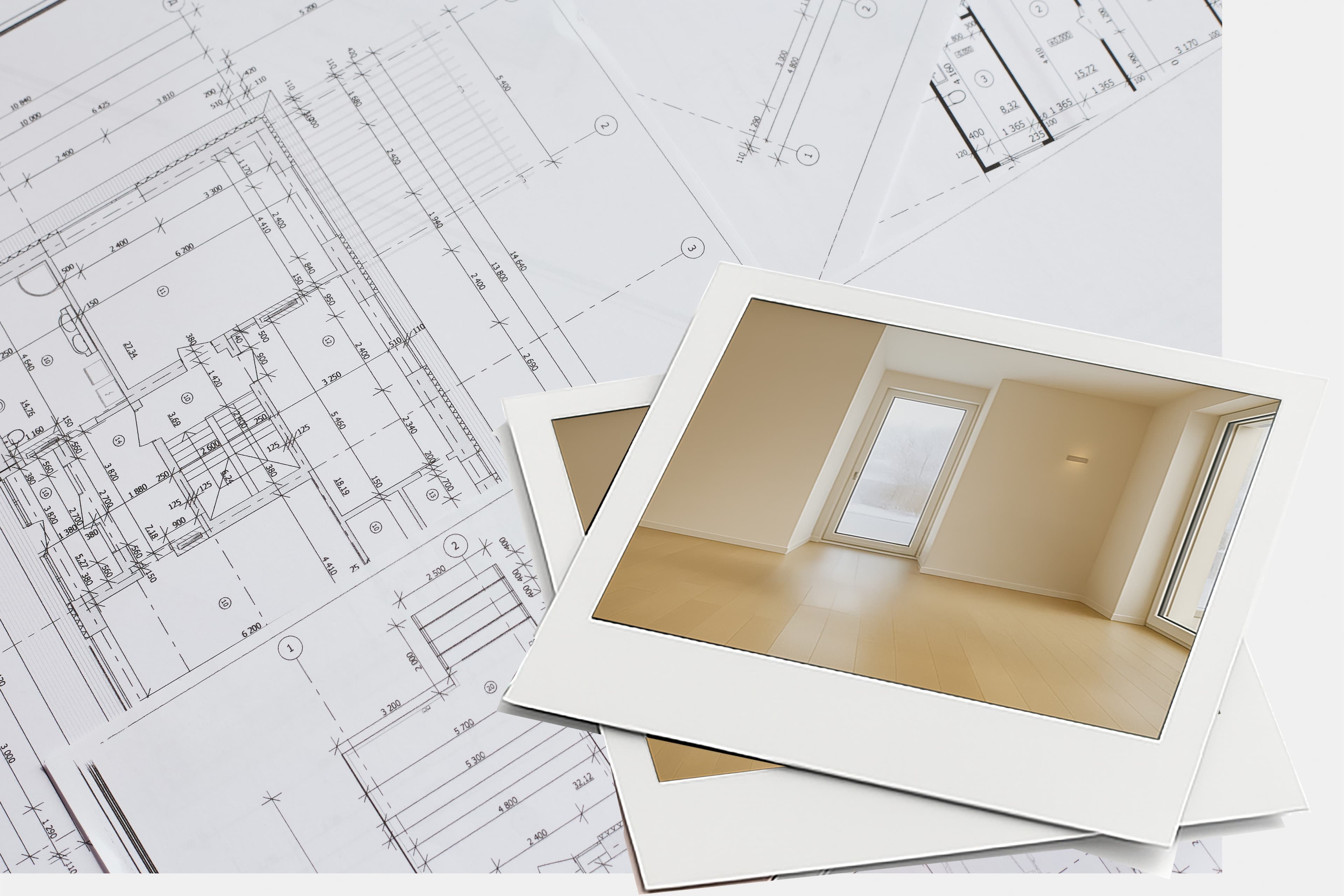 Zwei gedruckte Fotos eines leeren, hellen Raums mit Holzfußboden und großem Fenster liegen über Architekturplänen mit detaillierten Maßen und Zeichnungen.