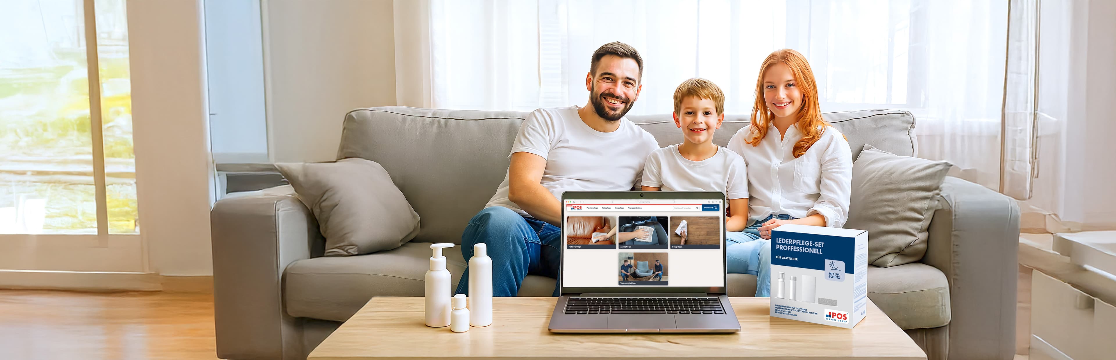 A smiling family of three sits on a sofa in a bright living room behind a coffee table with a laptop, hygiene bottles, and a test kit box, with the laptop displaying step-by-step instructions.